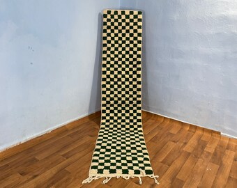May include: A long, narrow rug with a checkered pattern in black and white. The rug has a fringe on both ends.