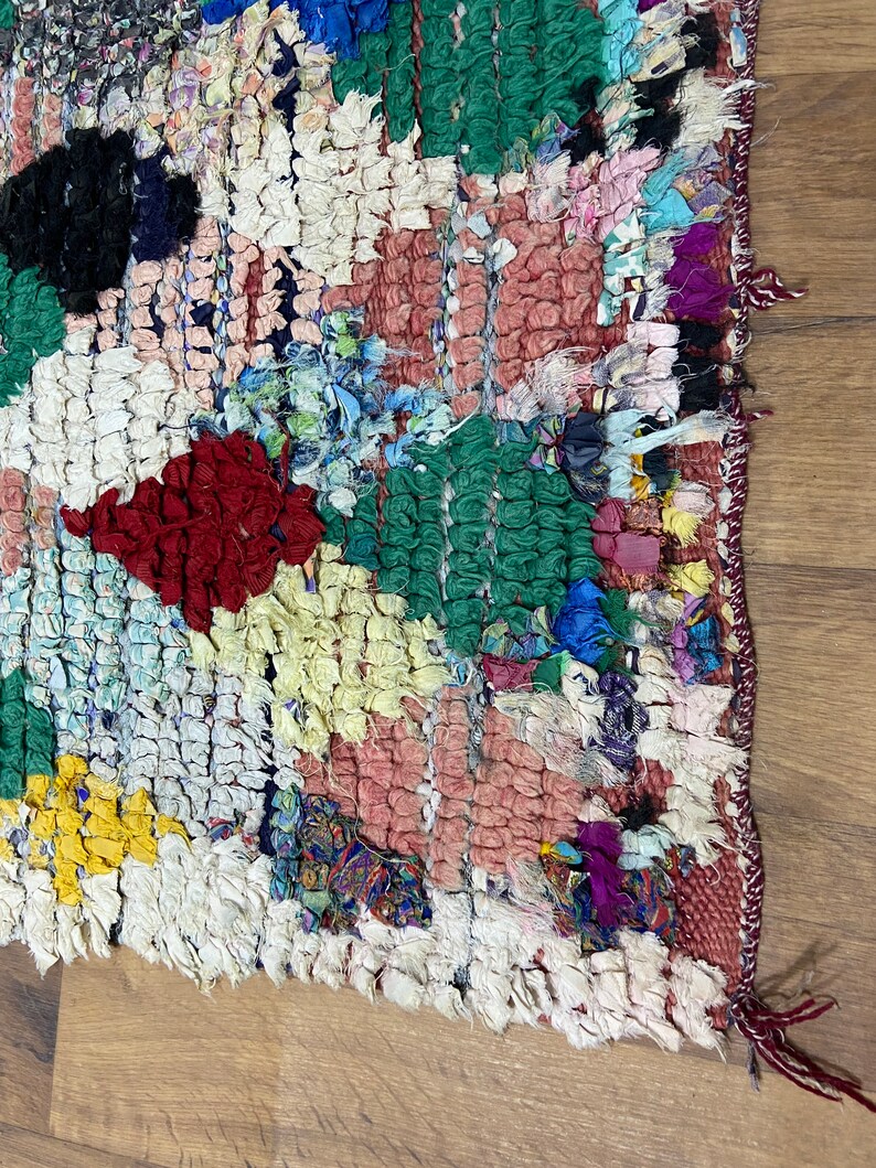 Puede incluir: Una alfombra colorida tejida a mano con un dise&ntilde;o de patchwork. La alfombra est&aacute; hecha de varias telas en tonos de rojo, verde, azul, amarillo y blanco. La alfombra tiene un borde deshilachado y est&aacute; hecha con un tejido texturizado &uacute;nico.