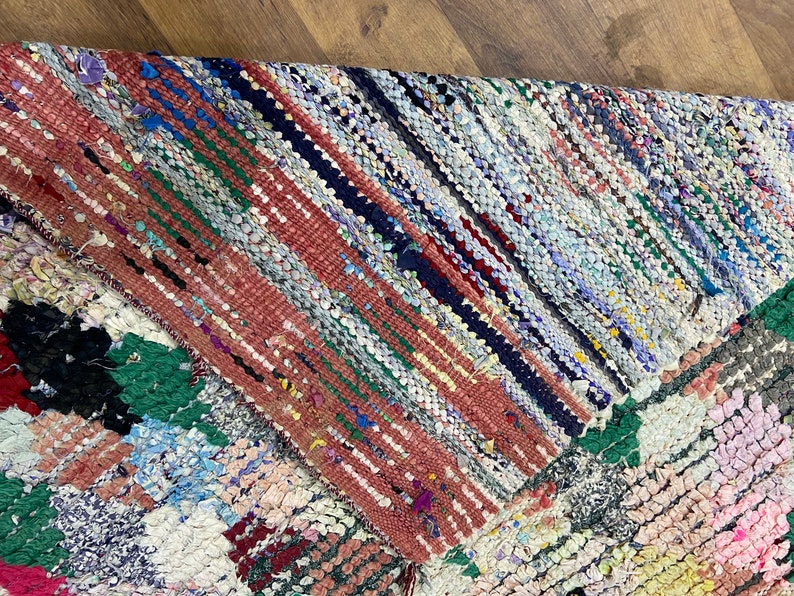 Puede incluir: Una alfombra de trapo colorida con un dise&ntilde;o de patchwork. La alfombra est&aacute; hecha de diferentes telas de colores que se han tejido juntas. La alfombra tiene un aspecto r&uacute;stico y vintage.