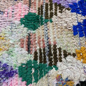 Puede incluir: Una alfombra colorida tejida a mano con un dise&ntilde;o de patchwork. La alfombra presenta varios colores, incluyendo rosa, verde, azul y blanco. La alfombra est&aacute; hecha de materiales reciclados y tiene una superficie texturizada &uacute;nica.