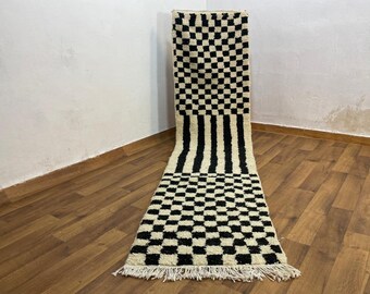 May include: Black and white checkered rug with a black and white striped section in the middle. The rug has a fringe border.