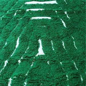 May include: A green and white striped bath mat with a fuzzy texture. The mat is made of a soft, absorbent material and is perfect for drying your feet after a shower or bath.