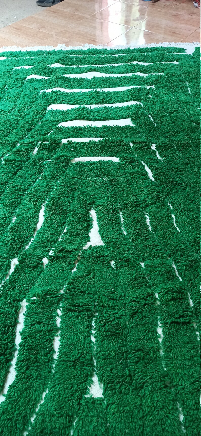 May include: A green and white striped bath mat with a fuzzy texture. The mat is made of a soft, absorbent material and is perfect for drying your feet after a shower or bath.