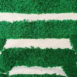 May include: Green bath mat with three white stripes. The mat is made of a soft, fluffy material.