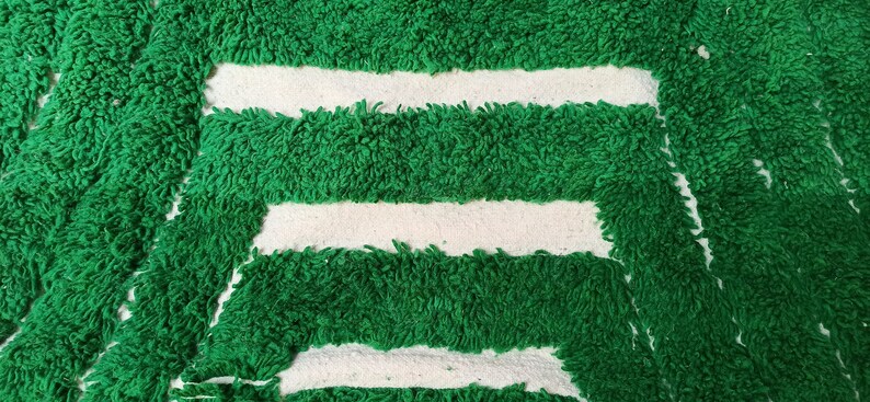 May include: Green bath mat with three white stripes. The mat is made of a soft, fluffy material.