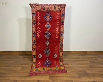 May include: A red, blue, and yellow patterned rug with fringe. The rug has a geometric design with diamonds and other shapes.