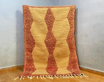 May include: A hand-woven rug with a geometric pattern of red and yellow diamonds. The rug has a fringe border and is made of wool.