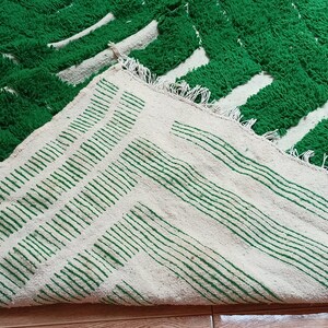 May include: A green and white striped rug with a fluffy texture. The rug is folded in half, showing both sides of the pattern.