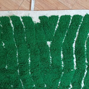 May include: A green and white rug with a wavy pattern. The rug is made of a soft, fluffy material.