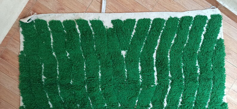 May include: A green and white rug with a wavy pattern. The rug is made of a soft, fluffy material.