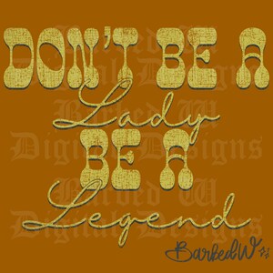 Op de afbeelding: Een digitaal ontwerp op een bruine achtergrond met de tekst "DON'T BE A Lady BE A Legend" in een vintage, getextureerd lettertype. Het ontwerp bevat de handtekening van de kunstenaar, "BarbedW".
