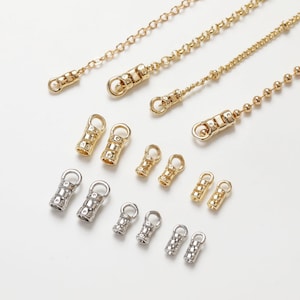 May include: Assortment of gold and silver metal chain end caps. The end caps are cylindrical with a decorative pattern and a small loop at each end.