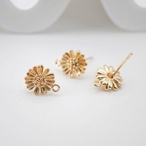 May include: Three gold-toned daisy flower earring findings with a loop on one side and a post on the other.