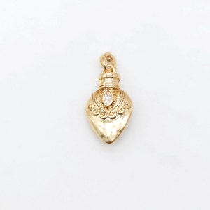 May include: A gold-tone pendant shaped like a heart-shaped bottle with an ornate design and a clear rhinestone in the center.