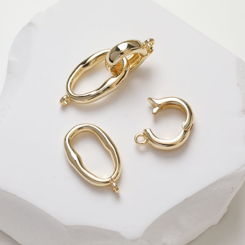 May include: Three gold-toned metal jewelry connectors. One connector is a double oval loop, one is a single oval loop, and the other is a single round loop.
