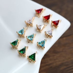 Puede incluir: Surtido de dijes en forma de triángulo con diferentes colores de diamantes de imitación. Los dijes son de color dorado y tienen un bucle en la parte superior para sujetarlos a joyas.