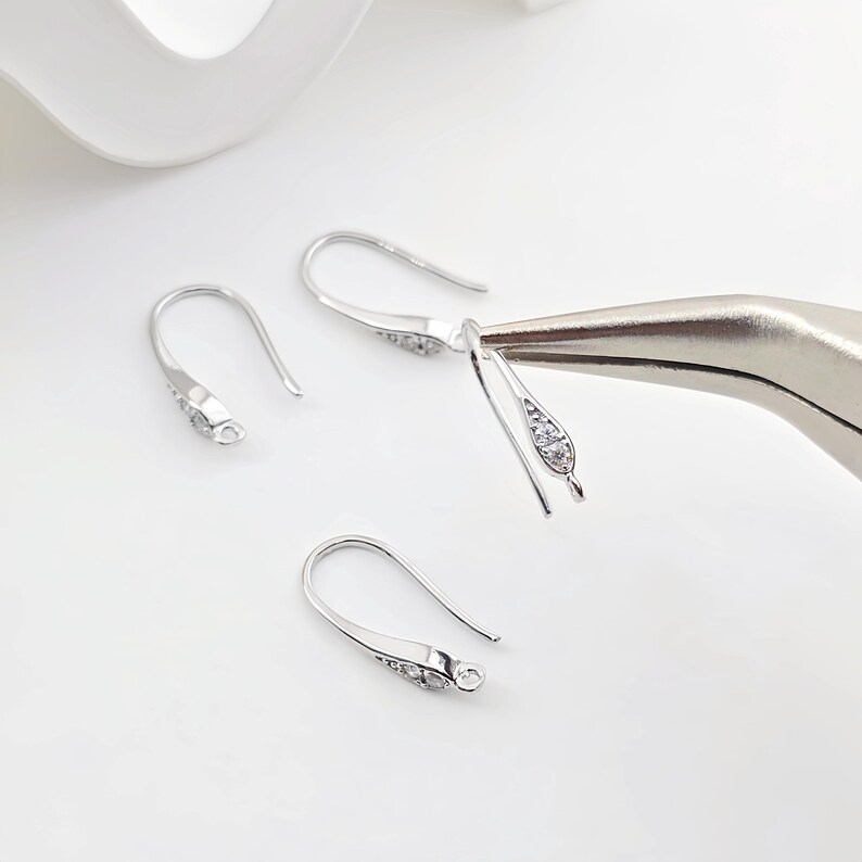 May include: Silver earring hooks with clear cubic zirconia stones. The hooks are designed to be used with jewelry making supplies.