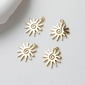 May include: Four gold-coloured sun charm pendants with a spiral design. Each charm has a loop for attaching to a necklace or bracelet.