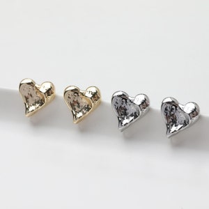 Pode incluir: Três pares de brincos em forma de coração em metal dourado, prateado e preto.