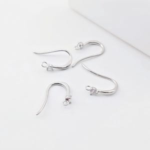 May include: Four silver earring hooks with clear crystal accents. The hooks are designed for hanging earrings.