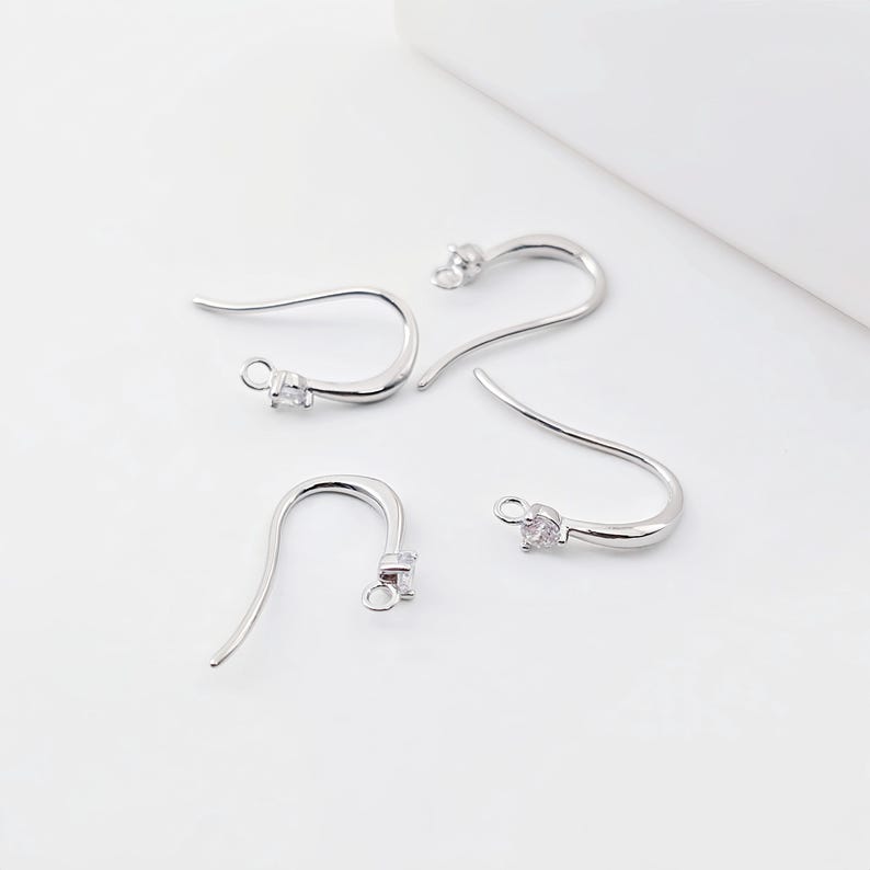 May include: Four silver earring hooks with clear crystal accents. The hooks are designed for hanging earrings.