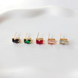 Può includere: Cinque perni per orecchini dorati con pietre rettangolari di vetro di diversi colori. Le pietre sono nere, verdi, rosse, rosa e blu.