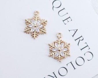 Puede incluir: Dos abalorios de copo de nieve dorados con detalles de cristal transparente. Los abalorios tienen un bucle en la parte superior para sujetarlos a joyas.
