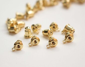 May include: A close-up of a group of gold-toned earring backs. The backs are small and round, with a small loop on the back for attaching to an earring.