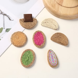 Può includere: Assortimento di sette decorazioni in paglia e tessuto intrecciati in varie forme e colori. Le decorazioni includono un semicerchio, un cerchio, un ovale e una forma a goccia. I colori includono rosa, verde, giallo e bianco.