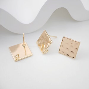 May include: A pair of gold square earrings with a hammered texture. One earring has a post back, while the other has a hook back.