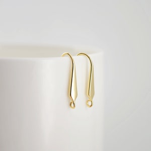 May include: A pair of gold-toned earring hooks with a teardrop-shaped design.