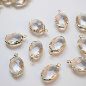 K&ouml;nnte beinhalten: Zehn klare, ovale Glasschmuckst&uuml;cke mit goldfarbenen Metallrahmen und &Ouml;sen. Die Charms sind facettiert und haben einen dezenten Schimmer.