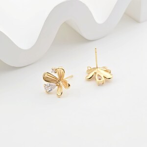 May include: Gold-tone flower-shaped earring findings with clear crystal accents. The findings have a post and a loop for attaching a charm or bead.