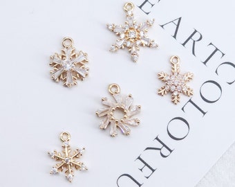 May include: Five gold snowflake charms with clear crystal accents. The charms are perfect for adding a touch of winter magic to jewelry projects.