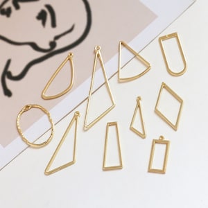 May include: A set of ten gold-colored metal frames in various geometric shapes, including circles, squares, rectangles, triangles, and diamonds. The frames are designed for crafting and jewelry making.