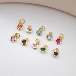 Può includere: Assortimento di ciondoli dorati con pietre rotonde colorate. I ciondoli presentano una varietà di colori, tra cui rosso, viola, blu, turchese, rosa, verde e rosso scuro.
