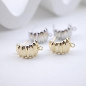 Peut inclure: Deux fermoirs de boucles d'oreilles dorés avec un design strié. Les fermoirs ont une petite boucle en haut pour les attacher aux boucles d'oreilles.
