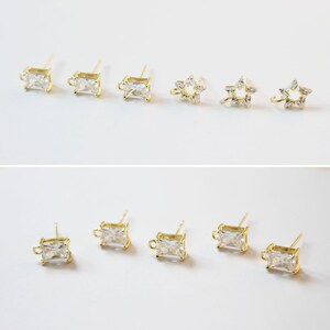 May include: A set of gold-tone earring findings with clear cubic zirconia stones. The findings are in the shape of a square and a star.