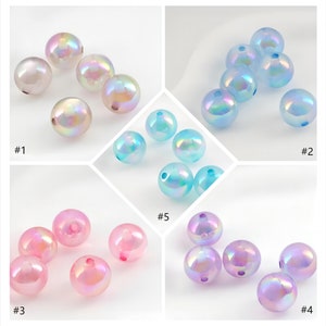 May include: Assortment of iridescent glass beads in various colors, including white, blue, pink, and purple. The beads are round and have a smooth, shiny finish.