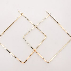 May include: A pair of gold square hoop earrings. The earrings are simple and elegant, and would be a great addition to any jewelry collection.