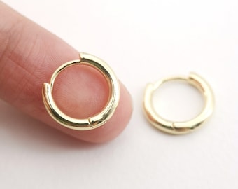 以下が含まれることがあります： 小さな金のフープイヤリングのペア。イヤリングはシンプルでエレガントで、どんなジュエリーコレクションにも最適です。