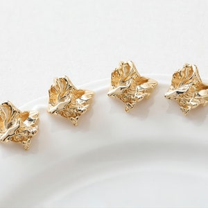 May include: Four gold-toned earrings with a textured, organic, abstract design. The earrings are displayed on a white surface.
