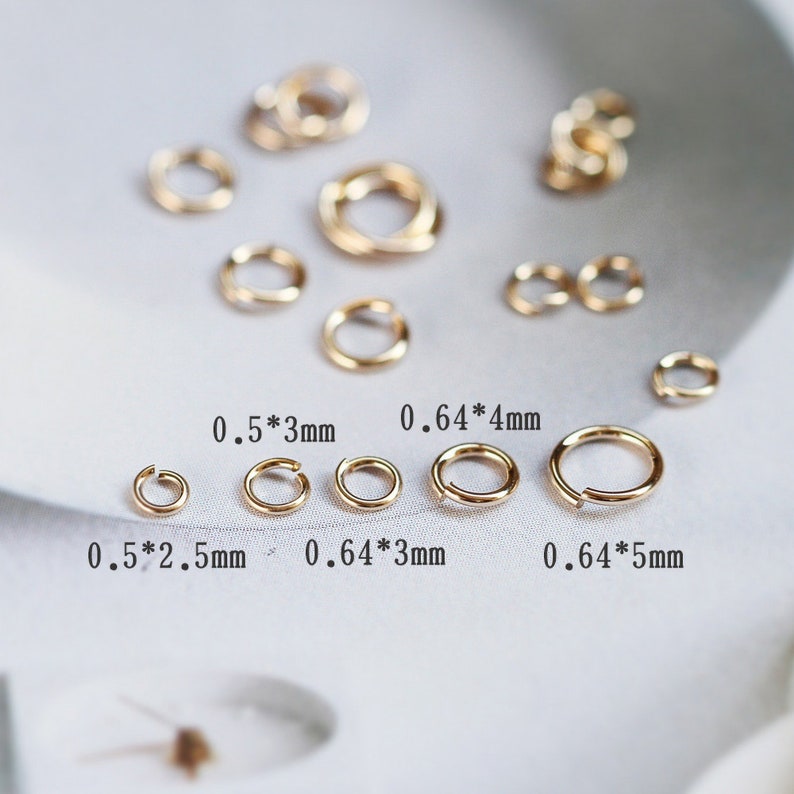 May include: Assortment of gold jump rings in various sizes. The jump rings are arranged in rows with their measurements labeled in millimeters.  0.5*3mm, 0.64*4mm, 0.5*2.5mm, 0.64*3mm, 0.64*5mm.