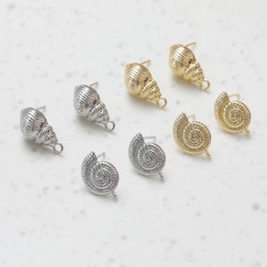 May include: Six pairs of gold and silver seashell-shaped earrings. The earrings are in the shape of a seashell and a spiral.