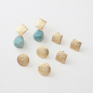 Könnte beinhalten: Ein Set aus sechs goldenen Ohrringen mit einem strukturierten Design. Die Ohrringe haben verschiedene Formen, darunter runde, quadratische und tropfenförmige.