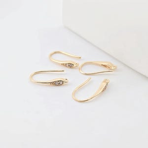 May include: Four gold-toned earring hooks with clear crystal accents. The hooks are designed to be used with jewelry making supplies.