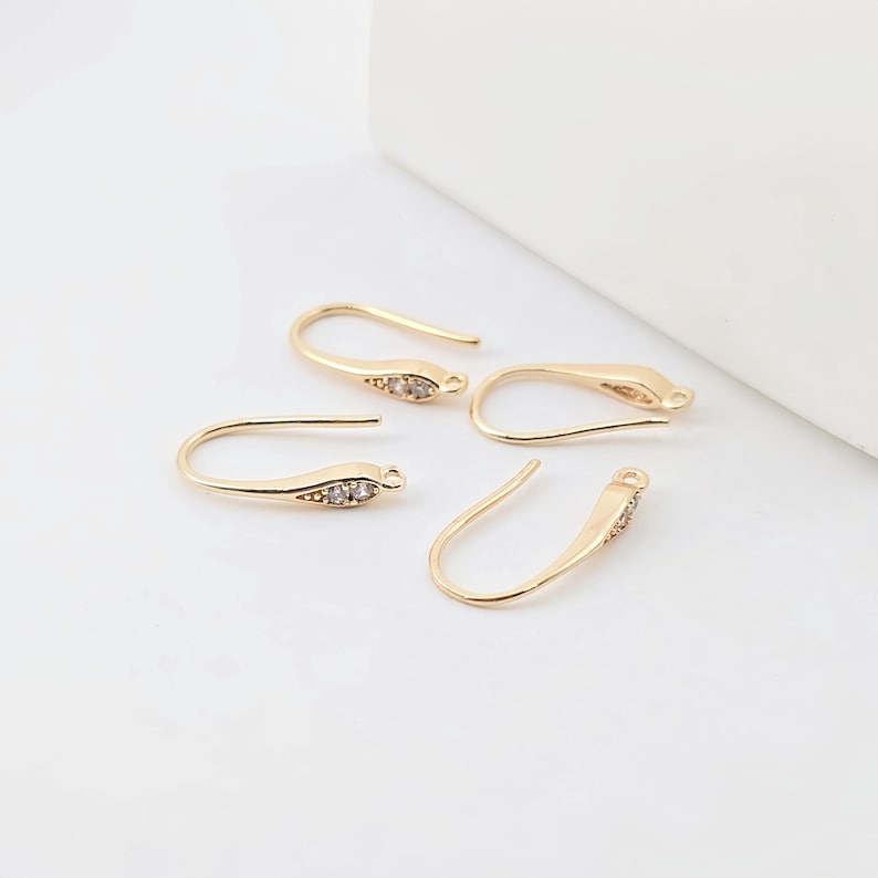 May include: Four gold-toned earring hooks with clear crystal accents. The hooks are designed to be used with jewelry making supplies.