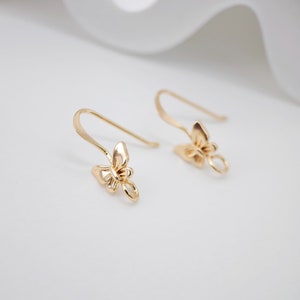 May include: A pair of gold butterfly shaped earring hooks. The hooks are made of metal and have a smooth finish.