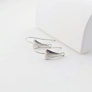 May include: Two silver earring hooks with a decorative fan-shaped design at the top.