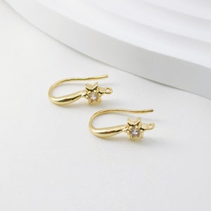 May include: Two gold-toned earring hooks with a small clear rhinestone star charm at the end of each hook.